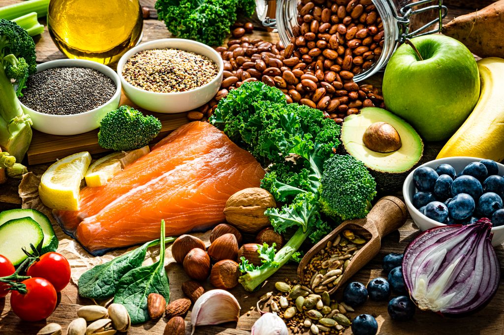 Healthy and well balanced group of food including fish, fruit, vegetables, nuts, seeds and more