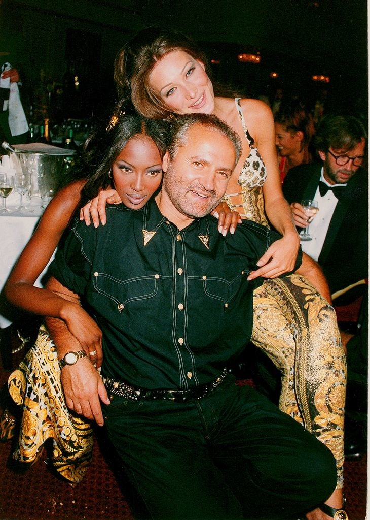 Carla Bruni and Naomi Campbell pose with designer Gianni Versace at The Rhythm of Life Fashion Ball in aid of the Rainforest Foundation at the Grosvenor House Hotel on May 31, 1992 in London, England. The event was hosted by rainforest campaigners Sting a