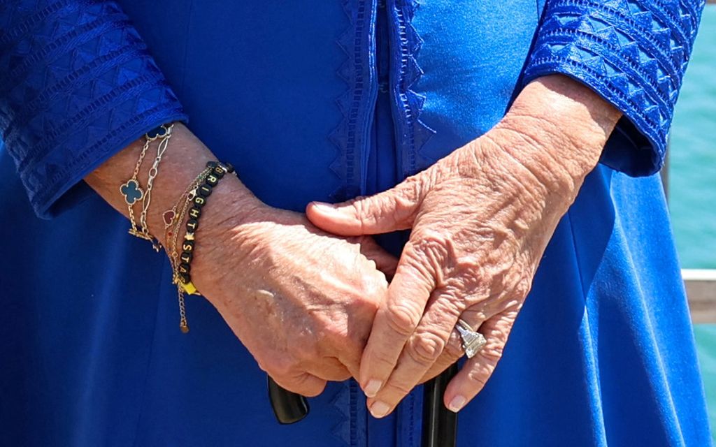 Close-up of Queen Camilla wearing blue dress and beaded friendship bracelet