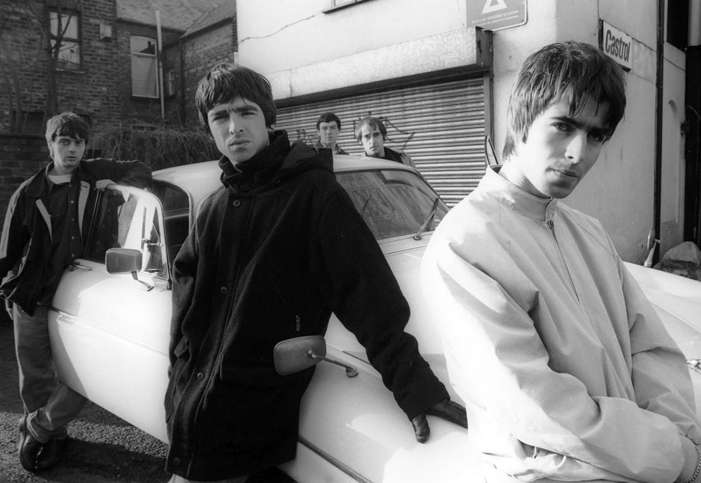 Group portrait of British rock band Oasis leaning against a Jaguar XJ6 car in Withington, Manchester, United Kingdom, 30th November 1993. L-R Paul McGuigan, Noel Gallagher, Tony McCarroll, Liam Gallagher, Paul Arthurs (aka Bonehead). (Photo by James Fry/Getty Images)