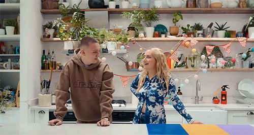 Aitch standing with Amelia Dimoldenberg in a kitchen