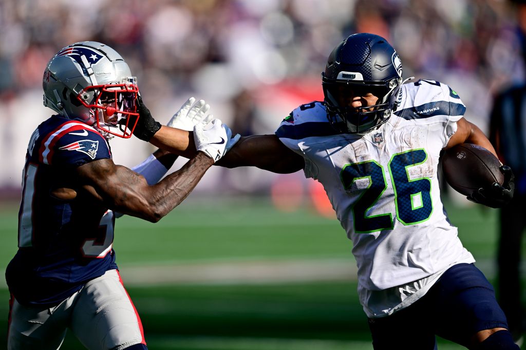 photo de Zach charbonnet des Seahawks de Seattle courant avec le ballon contre Jonathan Jones des New England Patriots