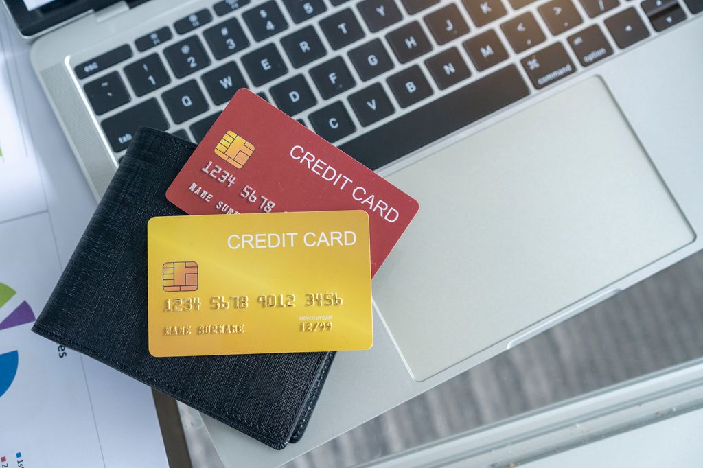 View of desk with credit cards and a wallet on computer laptop