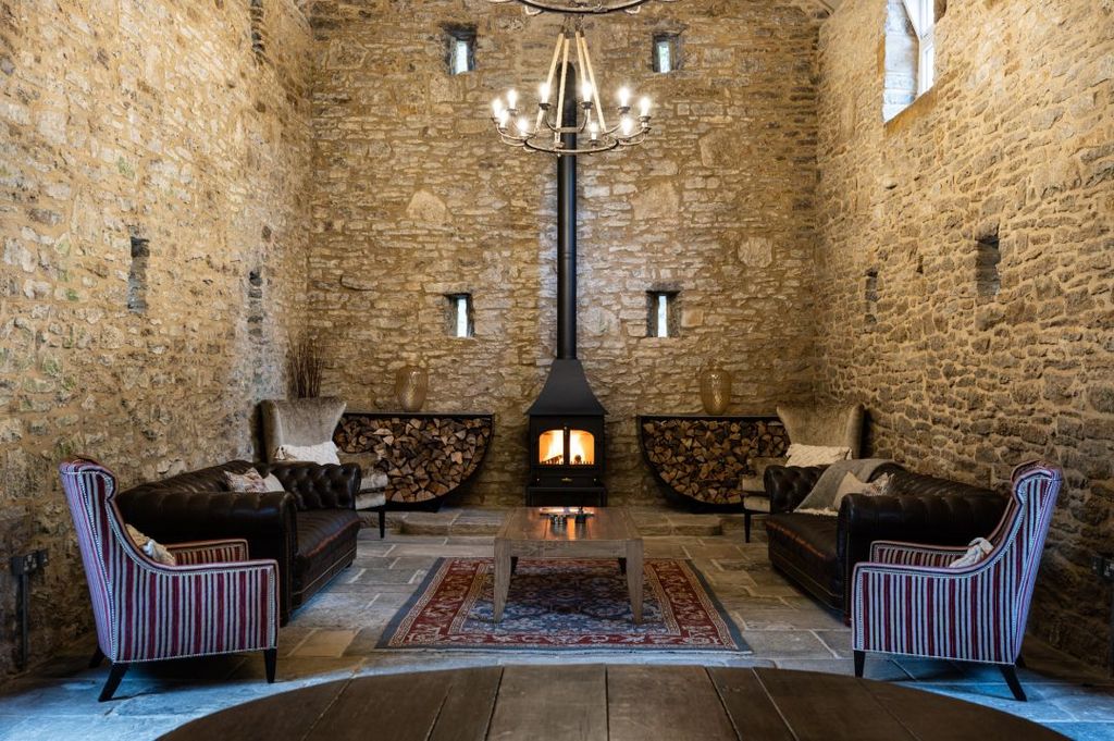 Barn conversion with chairs and a log burner