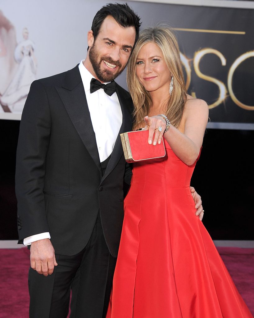 Jennifer aniston pointing next to justin theroux on red carpet