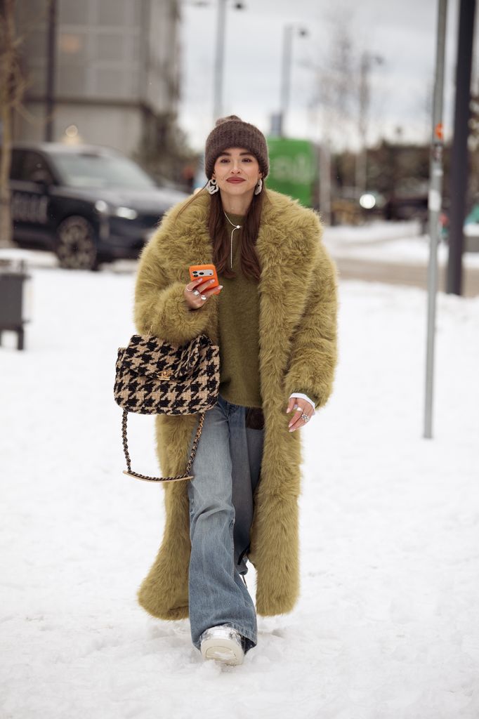 Evi Wave wears a green fluffy coat, matching jumper and coat plus jeans and trainers