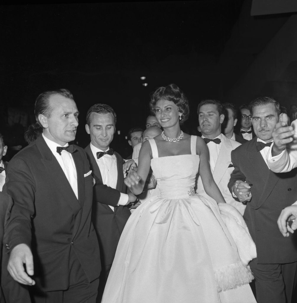 Sophia Loren in a white wide-circle dress surrounded by men 
