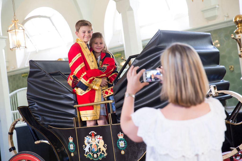 Children posing in the replica Landau in situ at the Royal Mews, Buckingham Palace, London