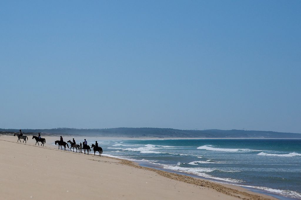 Tourists ride horse along Comporta beach
