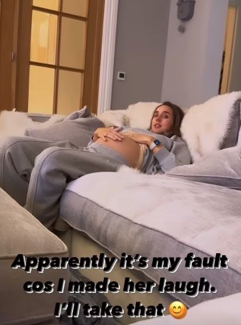 Pregnant Emily Andre cradles bare baby bump on sofa during Braxton Hicks contractions 