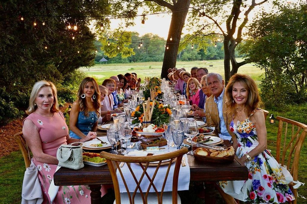 Susan Lucci sits at the front right at a long table, surrounded by friends in her garden