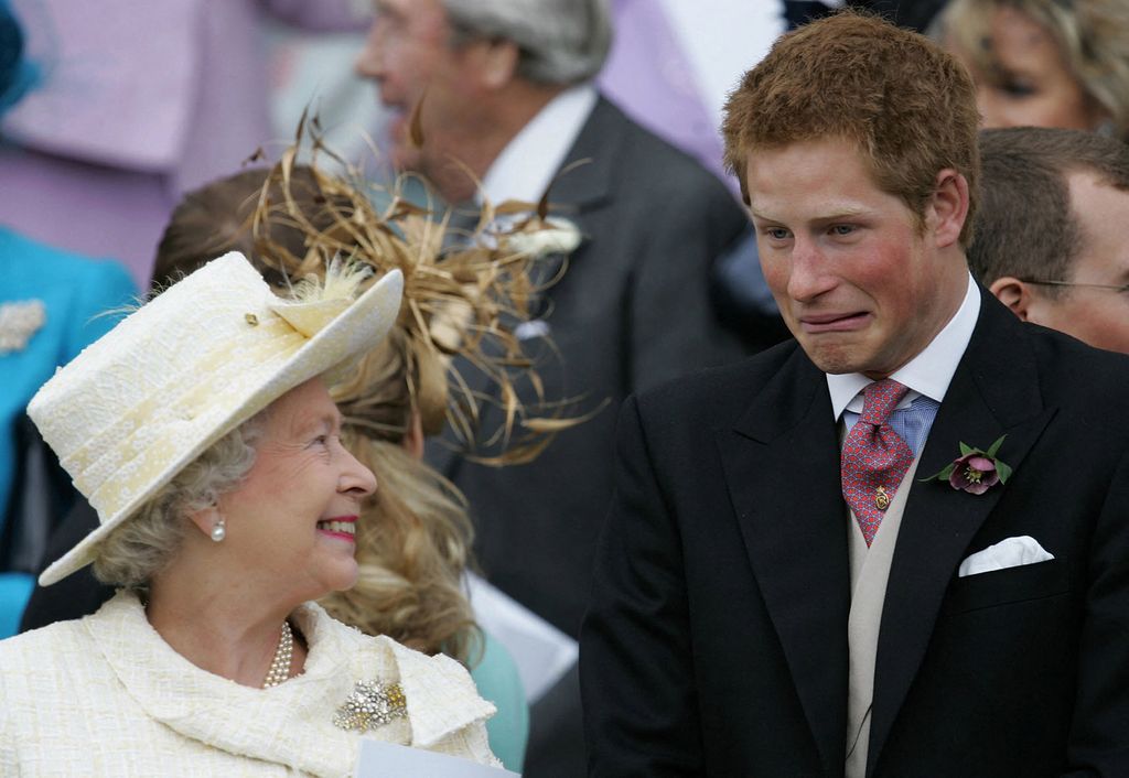 Prince Harry grimacing as he shares a joke with the Queen at Prince Charles' wedding