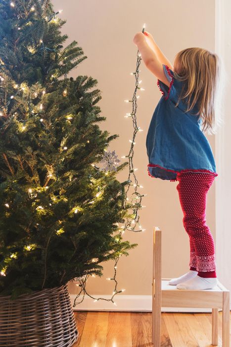 young child adding lights to a christmas tree