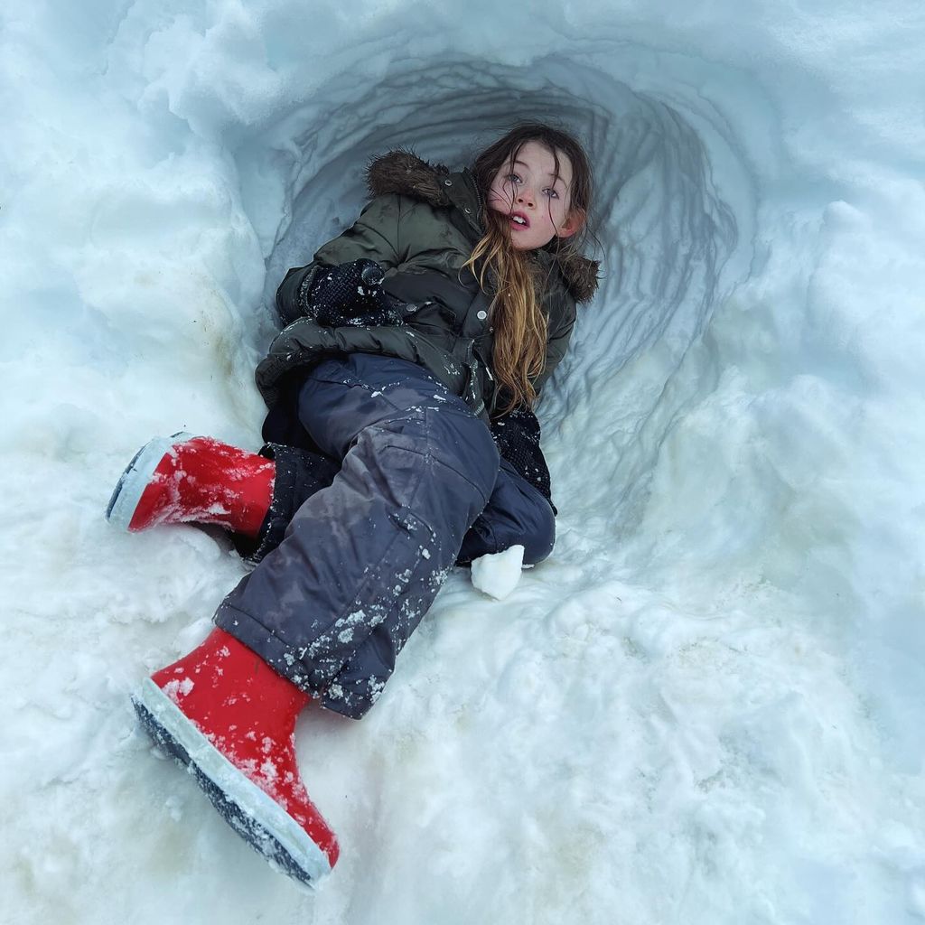 girl wearing green parka in snow cave 