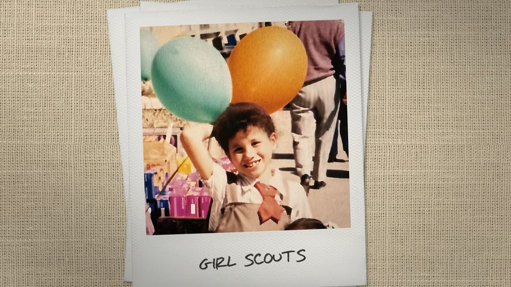 A photo of a girl dressed as a scout whilst holding two balloons