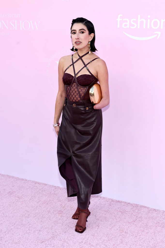 April Lockhart brought an avant-garde twist to the pink carpet, pairing a structured burgundy corset with a leather skirt. With gold statement earrings and a sleek hairstyle, her look combined high fashion elements with a hint of modern grunge.