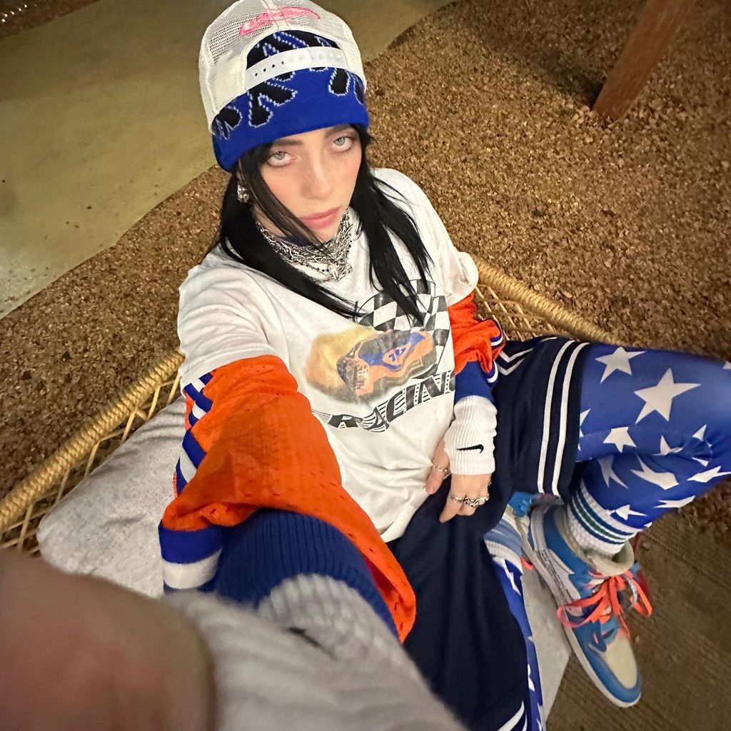 billie eilish in beanie hat and baseball cap wearing white red and blue baggy outfit