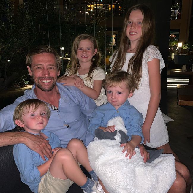 a photo of peter wearing a blue shirt at night time surrounded by his four children and two boys are wearing matching blue shirts and the little girls are wearing white dresses
