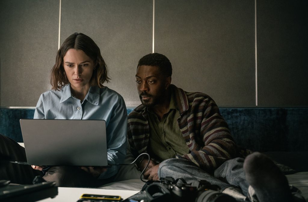 man and woman sitting on bed in front of laptop