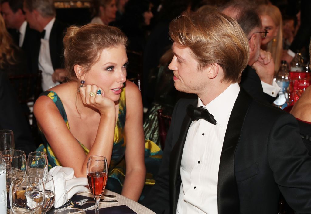 Taylor and Joe at an awards ceremony sat talking and looking at each other lovingly