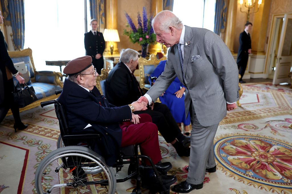 King Charles shaking hands with a man in a wheelchair