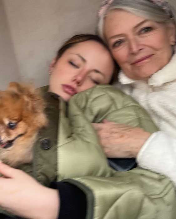 A blurry selfie of Kate leaning on her mums shoulder with a small dog in her arms