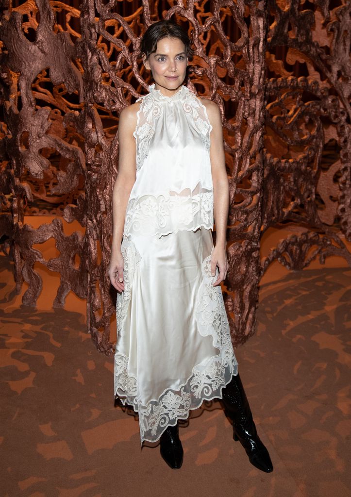 Katie Holmes wears a white silk halterneck top and matching skirt with lace edging, paired with black boots