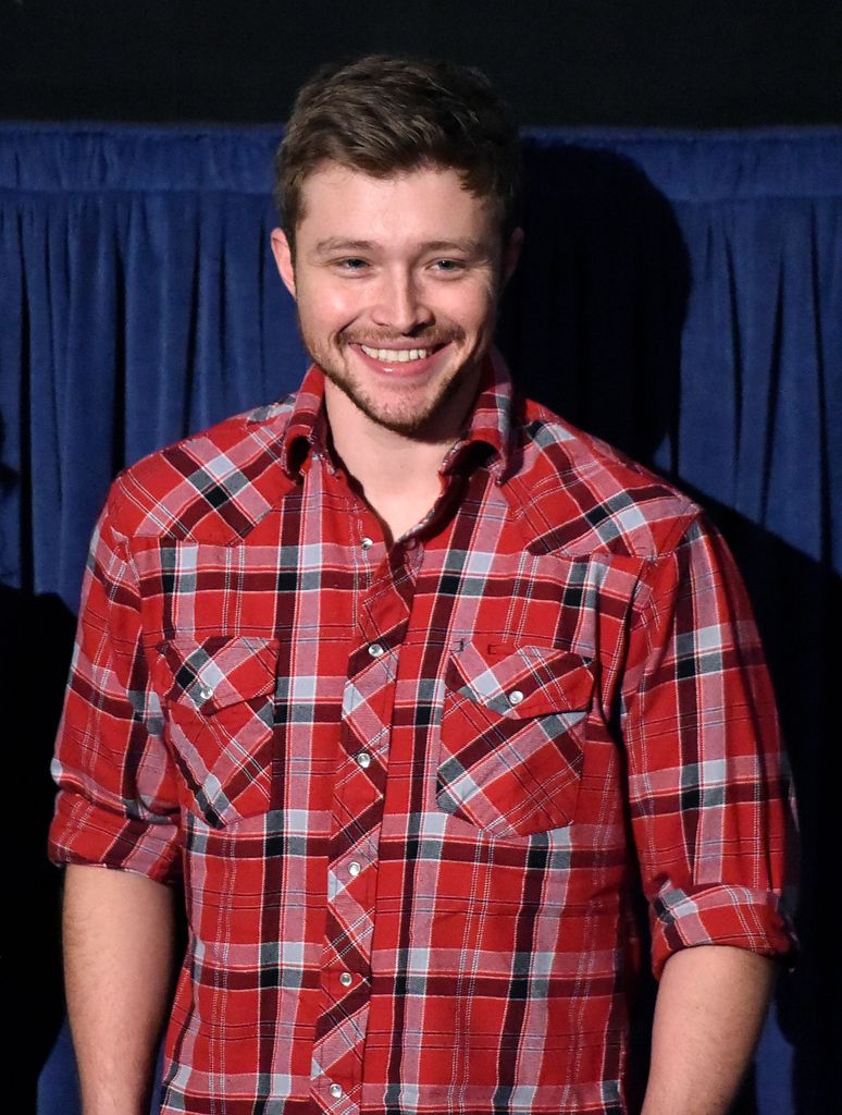 Sterling Knight porte une chemise en flanelle rouge et met ses mains dans ses poches.