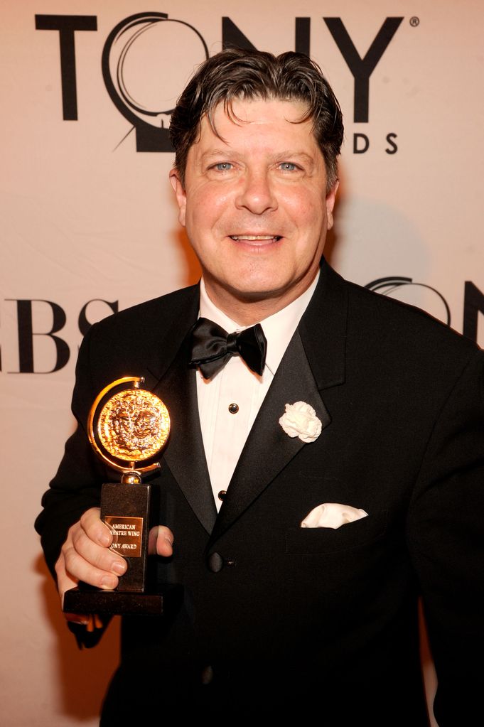 Michael McGrath smiles as he holds up Tony Award