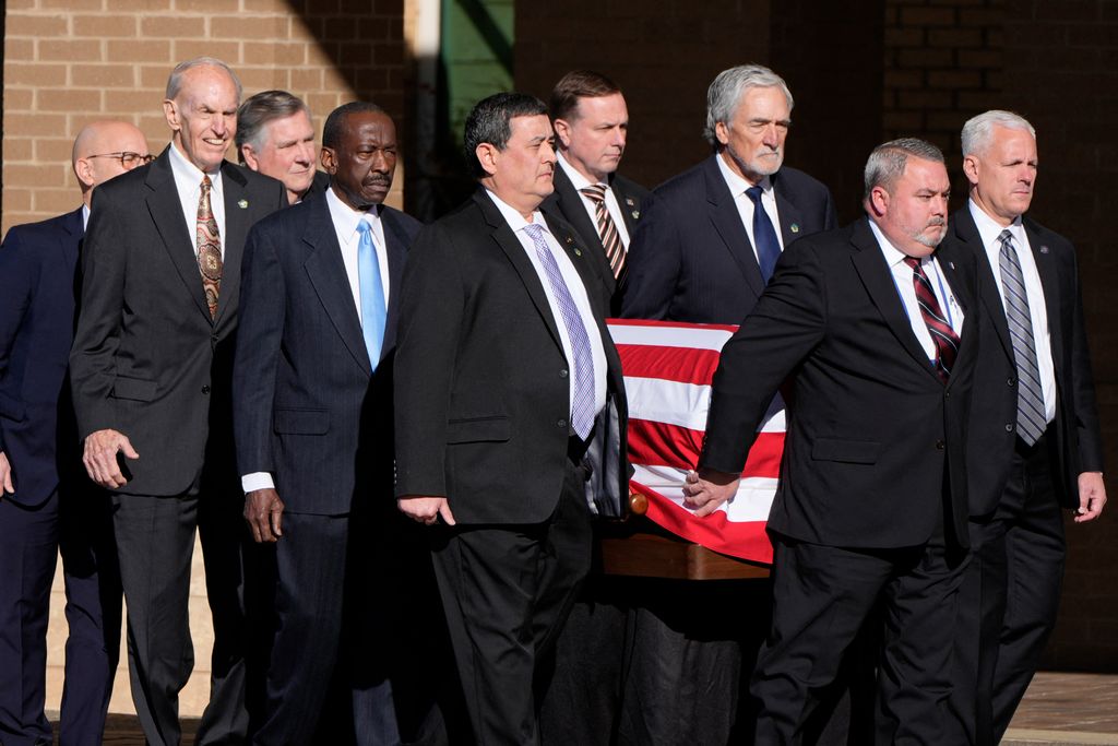 Former and current US Secret Service agents assigned to the Carter detail carry the flag-draped casket of former US President Jimmy Carter 