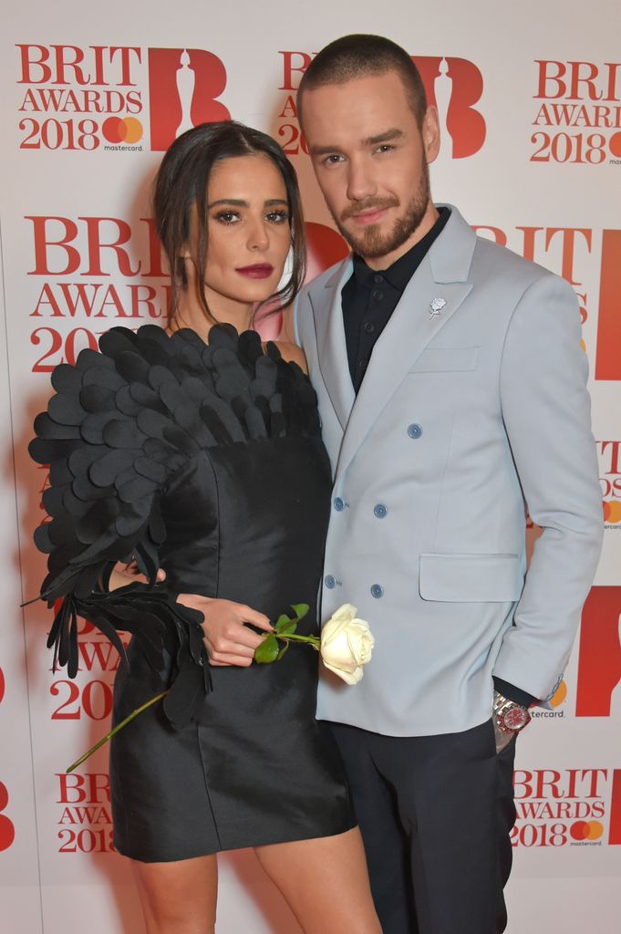 Cheryl in a black dress standing next to Liam Payne in a suit