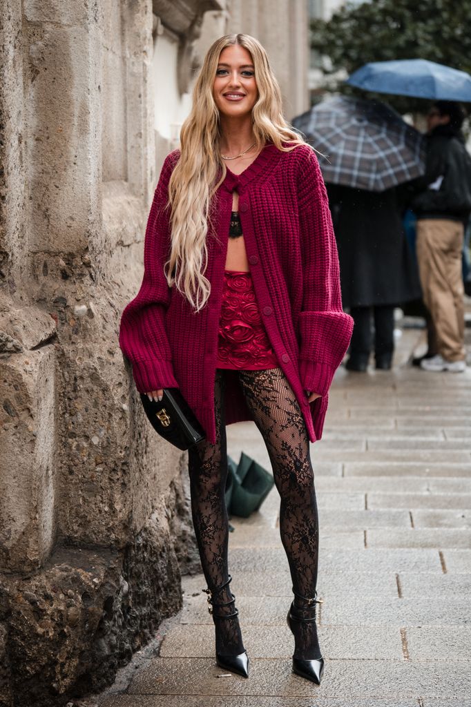  Emili Sindlev wears pink knitted cardigan, red flower decorated mini skirt, black lace tights, black heels, black Dolce and Gabbana bag, outside Blumarine, during the Milan Fashion Week - Womenswear Fall/Winter 2024-2025 