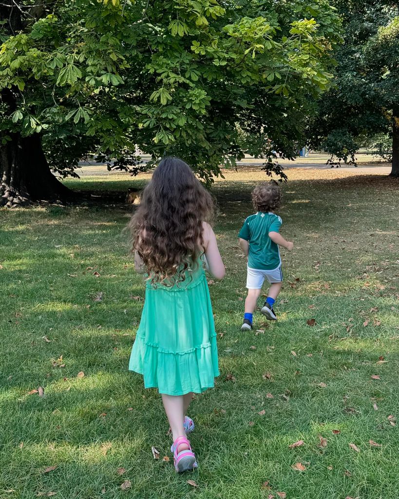 two young children walking through park