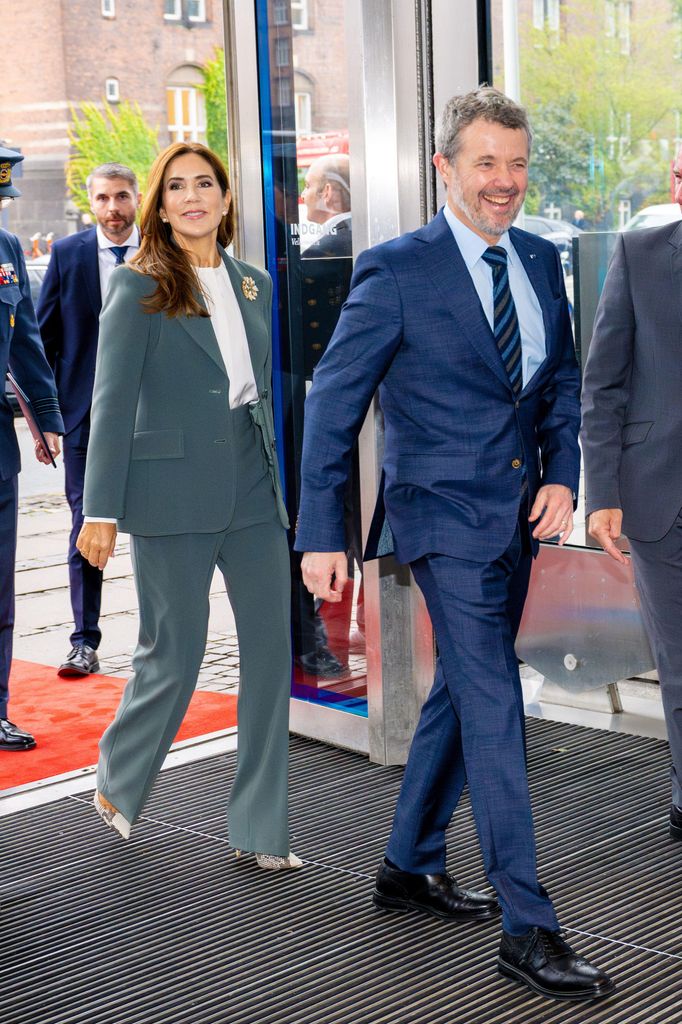 Queen Mary entrando no prédio em terno de duas peças com o rei Frederik