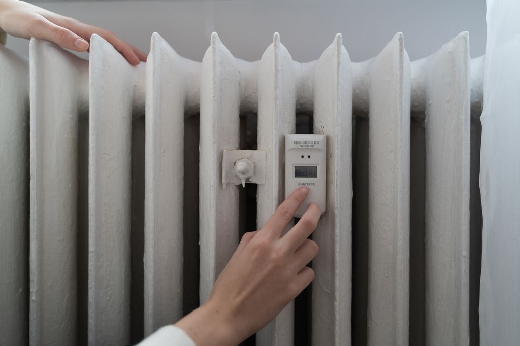 Young woman near the home radiator with temperature sensor