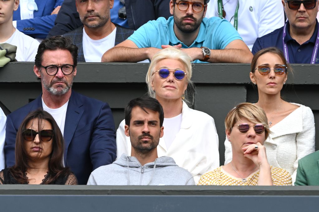 Hugh Jackman in a blue suit watching tennis with Deborra-Lee