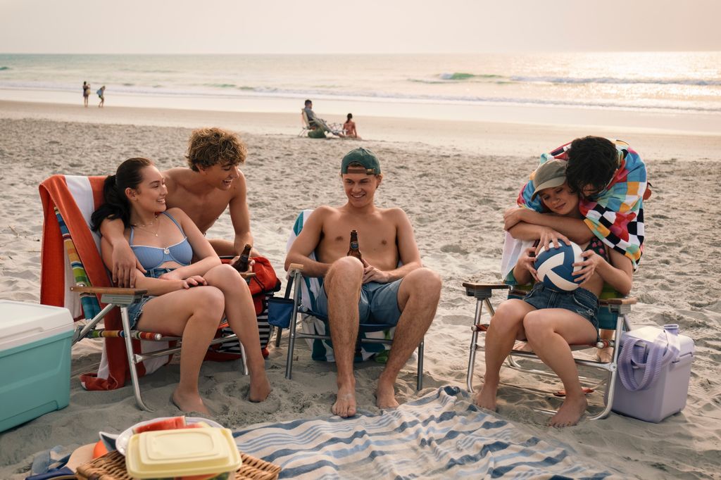 group of teens sitting in camp chairs on beach 