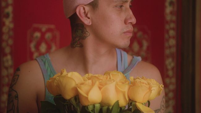 A man sat in front of yellow flowers