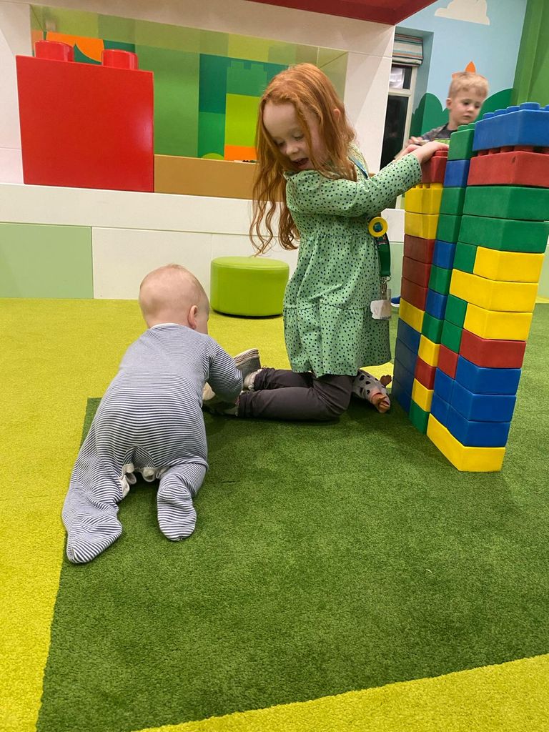 Girl with red hair and green dress, and baby play together