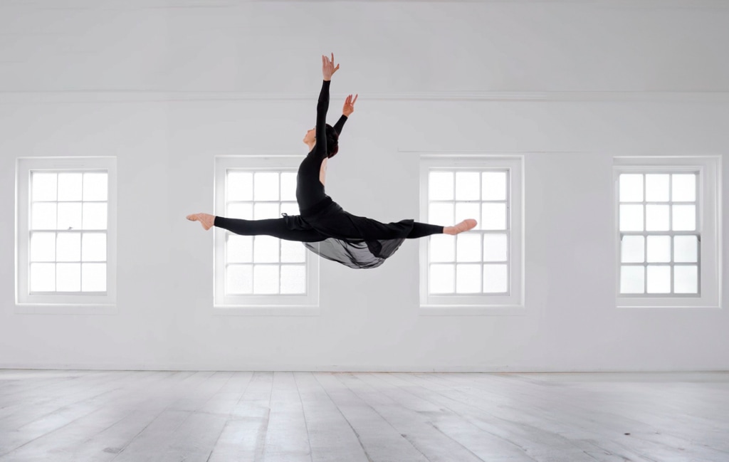 ballerina jumping in the air in a white studio 