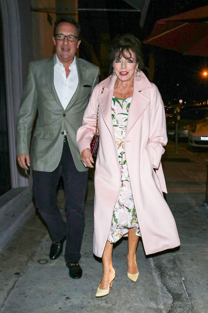 Joan Collins in pink coat and Percy Gibson on street at night