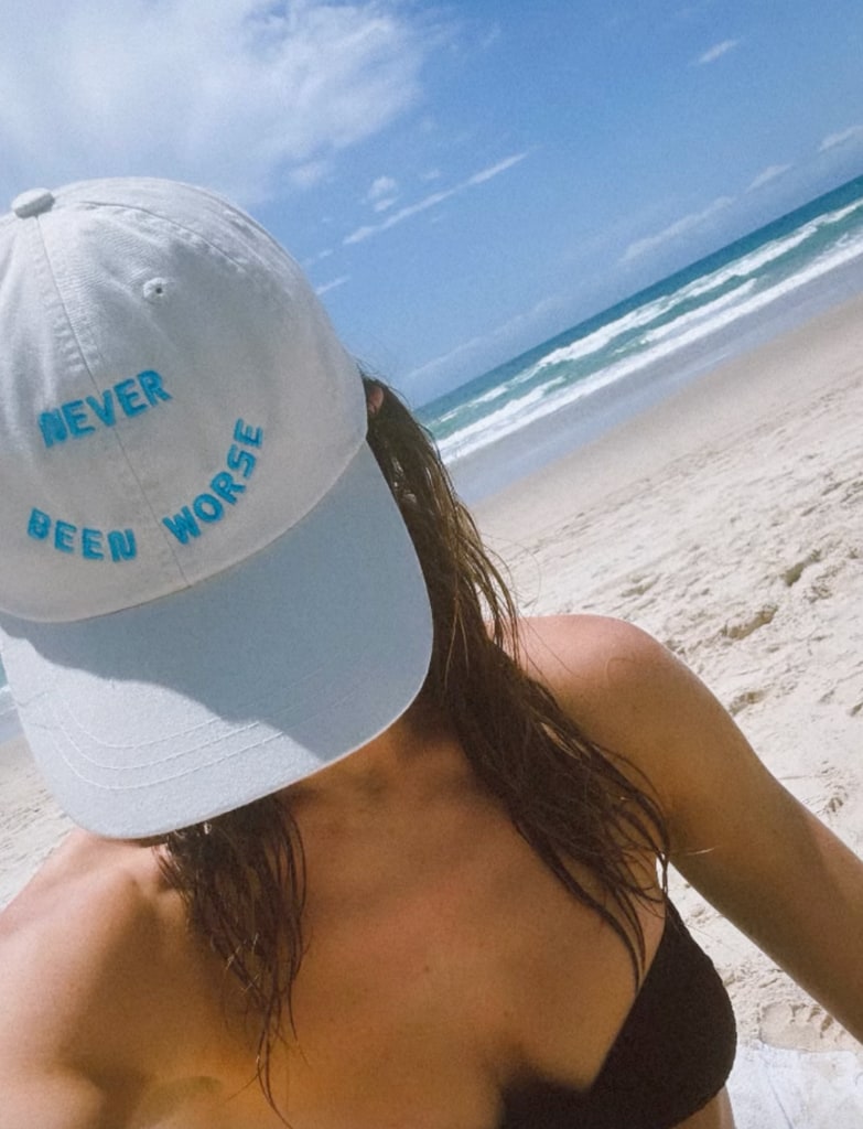 lily james in blue baseball cap on beach