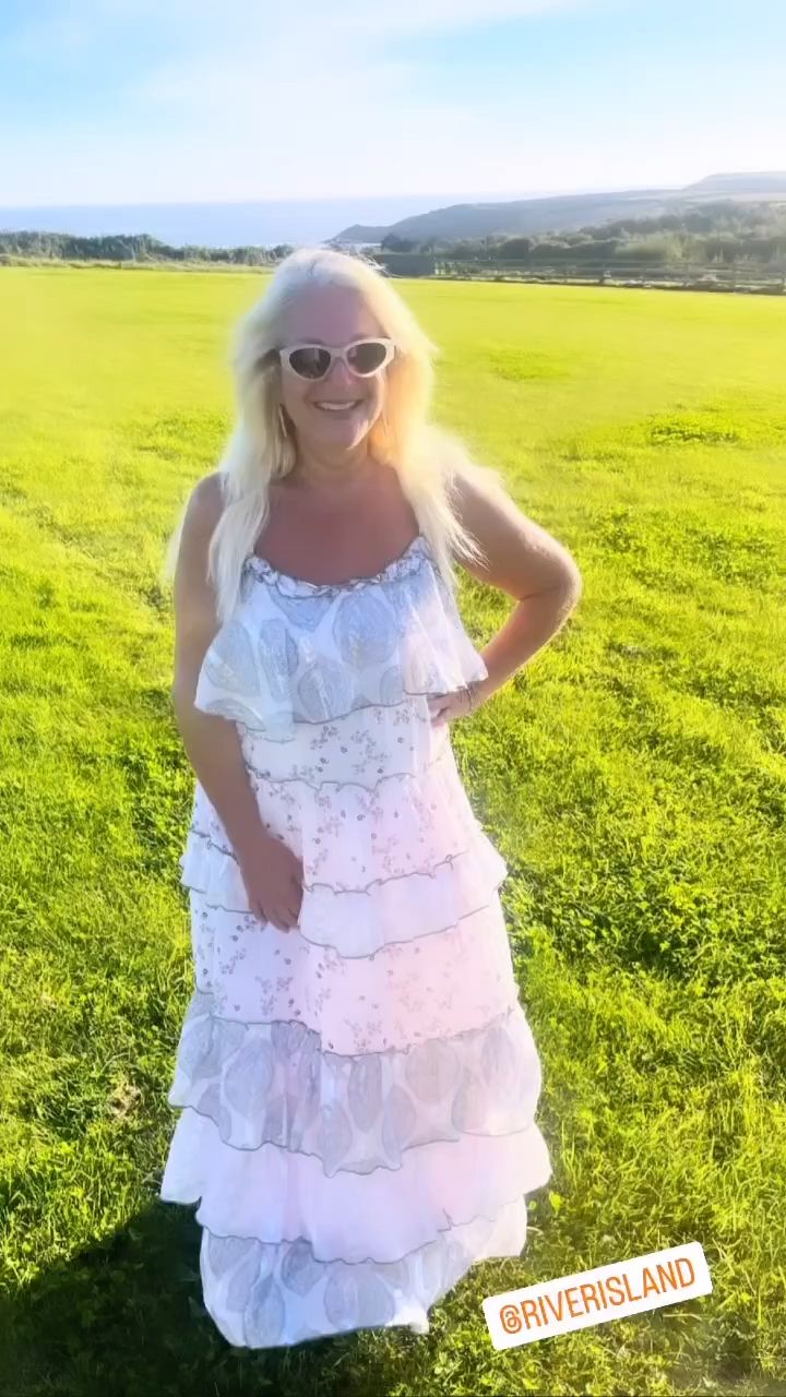 Vanessa Feltz looks radiant wearing a white summery ruffled dress while standing in a field