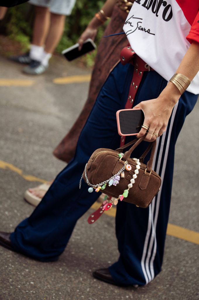A guest wears blue Adidas pants and a becharmed Miu Miu bag at Copenhagen Fashion Week