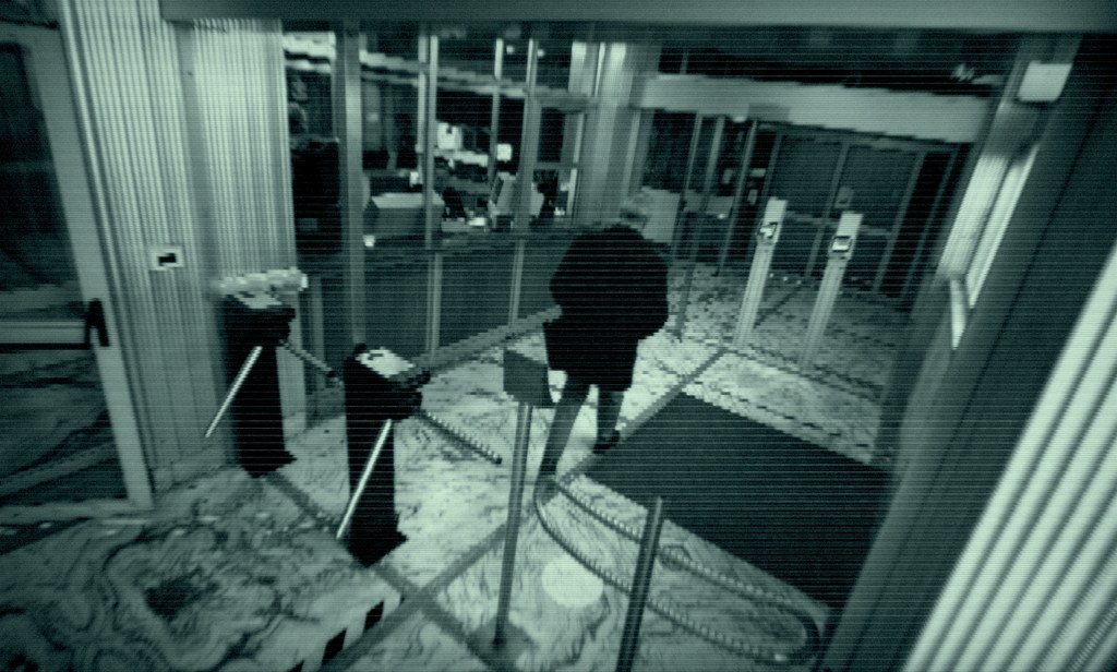 A black and white image shows a man leaving through security scanners