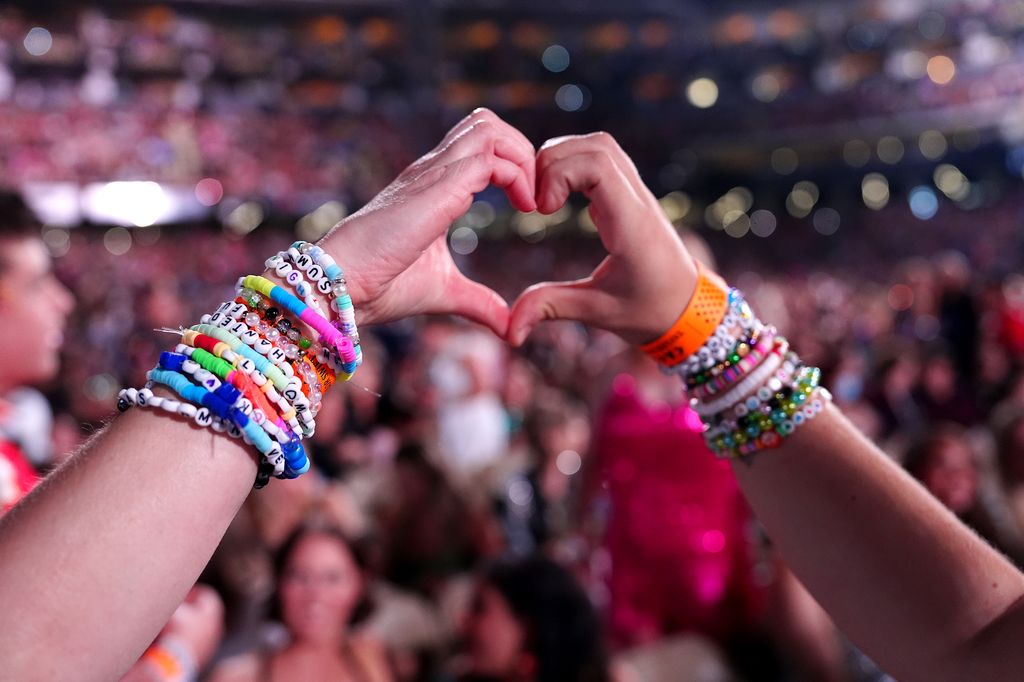 Fans wearing friendship bracelets make a hand heart at Caesars Superdome 