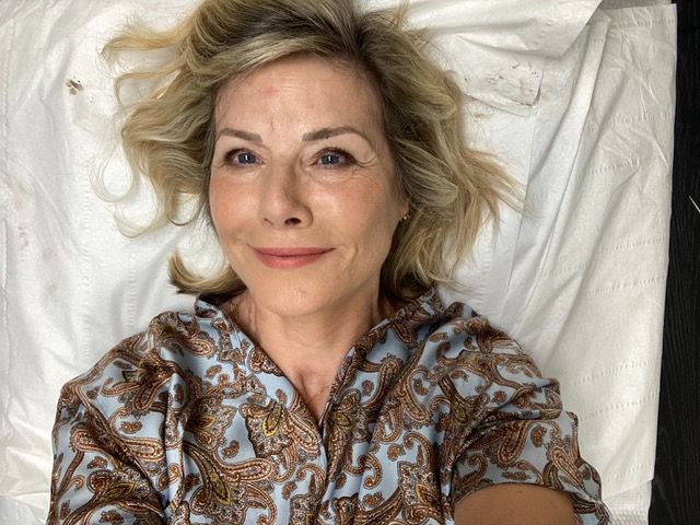 woman lying down in a print shirt after having her eyebrows tattooed