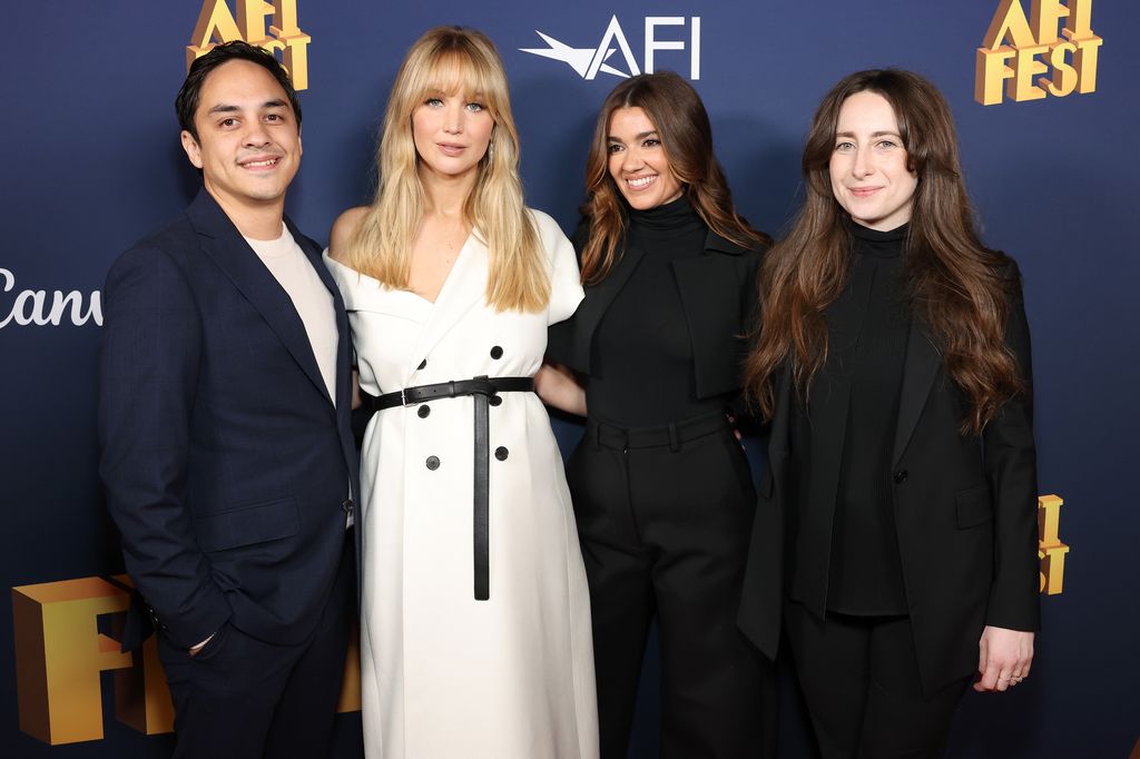 grupo de quatro pessoas posando no tapete vermelho na estreia