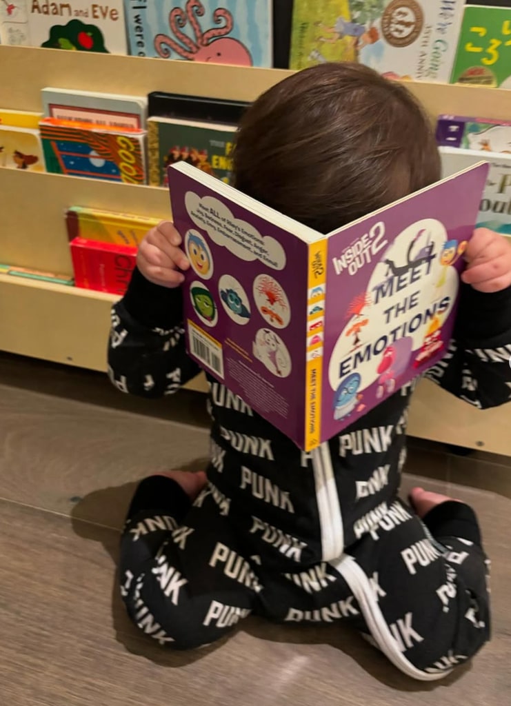 Photo shared by Kourtney Kardashian on Instagram November 2024 of her son Rocky covering his face with a book