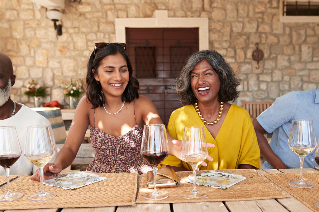 Happy female friends sitting together at table in winery during weekend party